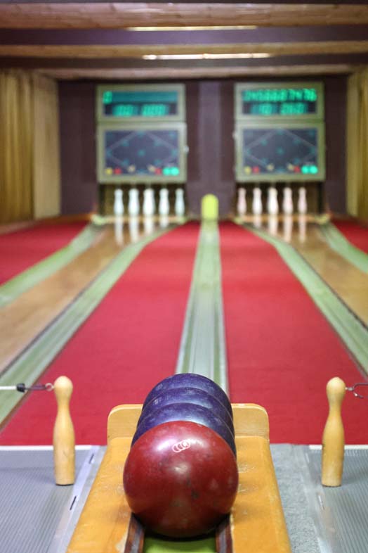 Bowling alley with two scissors lanes, 3 blue balls and one brown ball.