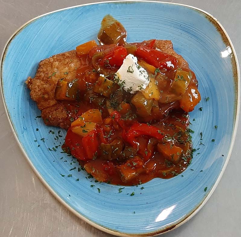 breaded schnitzel with red pepper sauce on blue plate