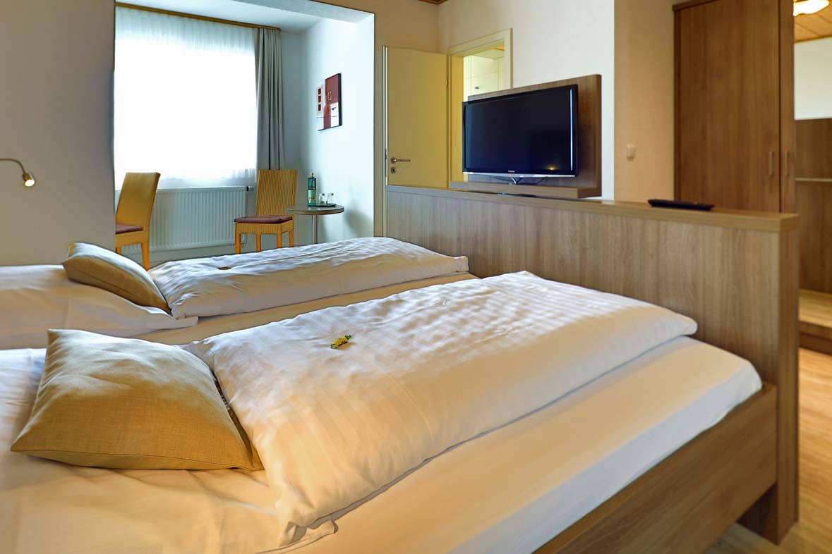 Double bed with white linens, at the foot of the bed is a TV
